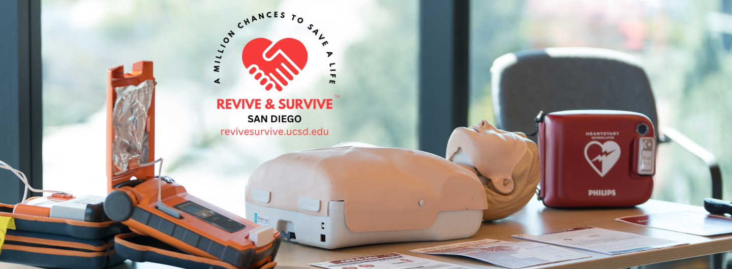 A mannequin on a table next to an AED machine. The logo above reads "A million chances to save a life: Revive and Survive San Diego"