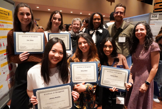 A group of faculty and students posing for a picture with their awards, which read "Certificate of recognition," followed by their names.